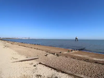 a beach with a person standing in the water at Flat 19 By The Beach in Harwich