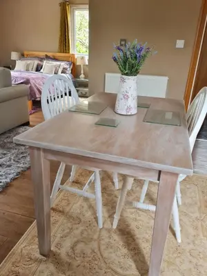 a dining room table with a vase of flowers on it at The Goat House in Purleigh