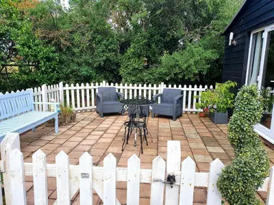 a patio with a table and chairs and a white fence at The Goat House in Purleigh