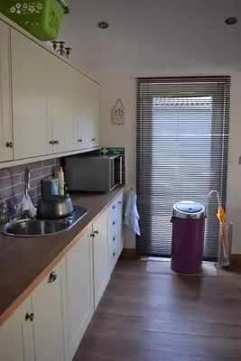 a kitchen with white cabinets and a sink and a window at The Goat House in Purleigh
