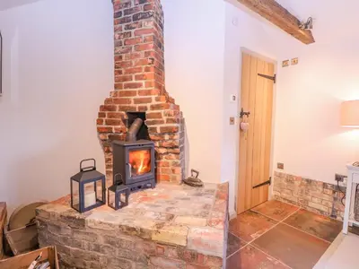 a brick fireplace in a living room with a stove at The Forge in Stowmarket