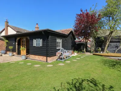 a small black house with a lawn in front of it at The Forge in Stowmarket