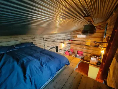 a bedroom with a bed in a wooden room at The Water Shack - Amazing tiny house retreat in Woodbridge