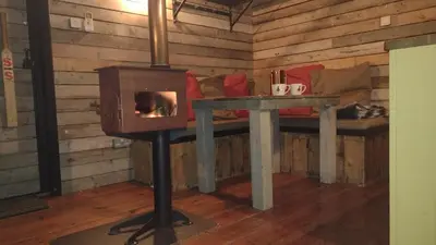 a stove in a room with a table and a couch at The Water Shack - Amazing tiny house retreat in Woodbridge
