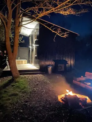 a fire in front of a building at night at The Water Shack - Amazing tiny house retreat in Woodbridge