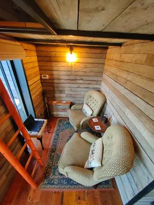 two chairs and a table in a room with wooden walls at The Water Shack - Amazing tiny house retreat in Woodbridge