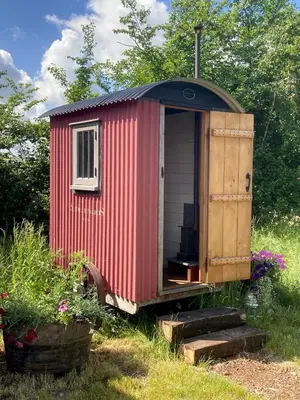 a red shed with a door and a window at Stompy's Hut in Laxfield