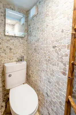 a bathroom with a toilet and a stone wall at Pebble Cottage - 6 Victoria Rd - Aldeburgh Coastal Cottages in Aldeburgh