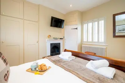 a bedroom with a bed with a tray of food on it at Pebble Cottage - 6 Victoria Rd - Aldeburgh Coastal Cottages in Aldeburgh