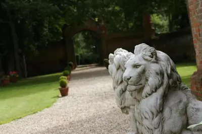 a statue of a lion sitting in a garden at Elizabethan Manor House - Sleeps 2-4 - Parking in Burnham on Crouch