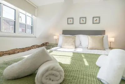 a bedroom with a large bed with towels on it at Candy Cottage, Halesworth in Halesworth
