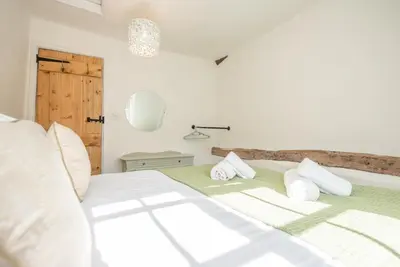 a white bedroom with a bed with white pillows at Candy Cottage, Halesworth in Halesworth