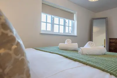 a bedroom with a bed with two towels on it at Candy Cottage, Halesworth in Halesworth