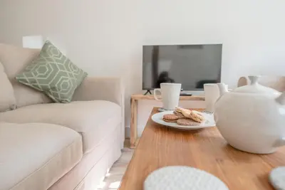 a living room with a couch and a table with a vase at Candy Cottage, Halesworth in Halesworth