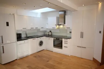 a kitchen with white cabinets and a washer and dryer at Cambridge city centre immaculate 2 bed apartment in Cambridge
