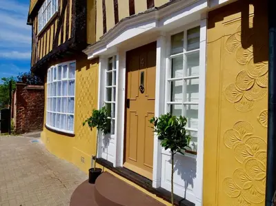 a yellow building with a yellow door and windows at Huge Deluxe 600 Year Old Essex Manor, Hot Tub, Cinema Room, Sky Tv in Saffron Walden