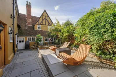 a patio with chairs and a table and a house at Huge Deluxe 600 Year Old Essex Manor, Hot Tub, Cinema Room, Sky Tv in Saffron Walden