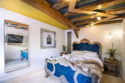 a bedroom with a blue bed and a mirror at Huge Deluxe 600 Year Old Essex Manor, Hot Tub, Cinema Room, Sky Tv in Saffron Walden