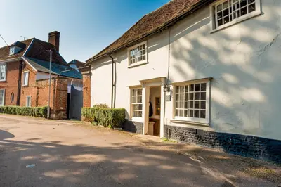 a white house with a driveway in front of it at Miller Cottage a luxury 1550's cottage in the Historic centre of Saffron Walden in Saffron Walden