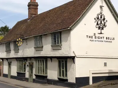 a white building with a sign on the side of it at Miller Cottage a luxury 1550's cottage in the Historic centre of Saffron Walden in Saffron Walden