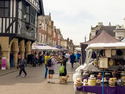 a group of people walking down a street with a food stand at Miller Cottage a luxury 1550's cottage in the Historic centre of Saffron Walden in Saffron Walden