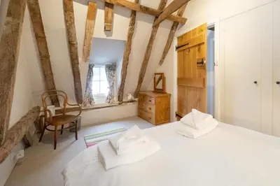 a bedroom with a white bed and a chair at White Cottage, Iken - Aldeburgh Coastal Cottages in Snape