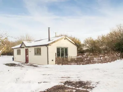 a small white house in the snow at Bramley Cottage in North Weald