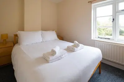 a bedroom with a white bed with towels on it at Mere Cottage - Aldeburgh Coastal Cottages in Thorpeness
