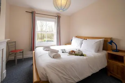 a bedroom with a large white bed with towels on it at Mere Cottage - Aldeburgh Coastal Cottages in Thorpeness