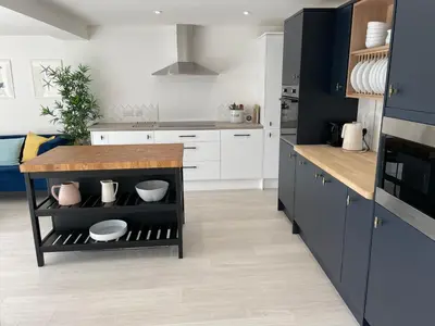 a kitchen with white cabinets and a wooden counter at Island House in West Mersea