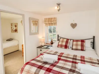 a bedroom with a bed with a plaid blanket at 2 Greensleeves in Saxmundham