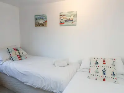 a bedroom with two beds and two pictures on the wall at 2 Greensleeves in Saxmundham