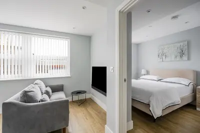 a bedroom with a bed and a couch and a television at Luxury Apartment in Chelmsford Bond Street with Sky TV, Movies & Netflix in Chelmsford