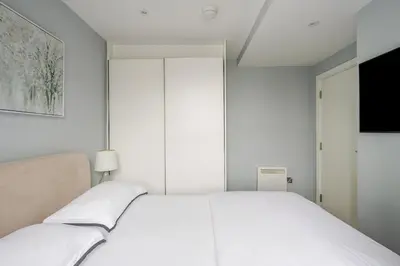a white bedroom with a white bed and a television at Luxury Apartment in Chelmsford Bond Street with Sky TV, Movies & Netflix in Chelmsford