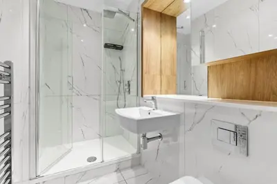 a white bathroom with a shower and a sink at Luxury Apartment in Chelmsford Bond Street with Sky TV, Movies & Netflix in Chelmsford