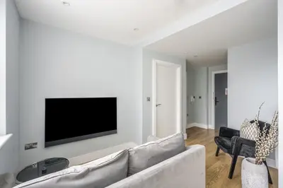 a living room with a couch and a tv on a wall at Luxury Apartment in Chelmsford Bond Street with Sky TV, Movies & Netflix in Chelmsford
