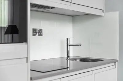 a kitchen with a sink and white cabinets at Luxury Apartment in Chelmsford Bond Street with Sky TV, Movies & Netflix in Chelmsford