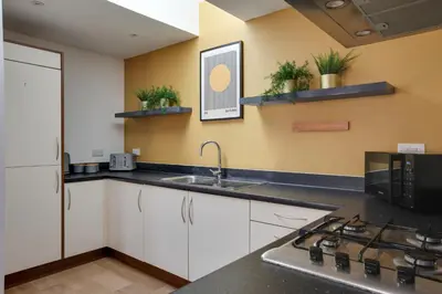 a kitchen with white cabinets and a sink and a stove at Two Bedroom Coach House - Free Allocated Parking for 2 vehicles - Central Colchester in Colchester