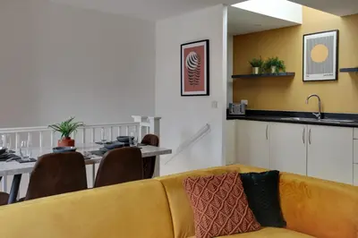 a living room with a yellow couch and a table at Two Bedroom Coach House - Free Allocated Parking for 2 vehicles - Central Colchester in Colchester