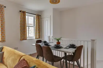a living room with a table and a couch at Two Bedroom Coach House - Free Allocated Parking for 2 vehicles - Central Colchester in Colchester