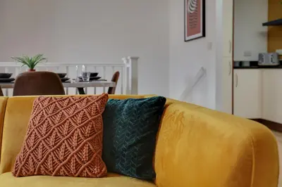 a yellow couch with two pillows on top of it at Two Bedroom Coach House - Free Allocated Parking for 2 vehicles - Central Colchester in Colchester