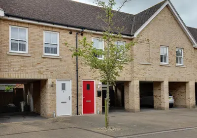 a brick building with a red door and a tree at Two Bedroom Coach House - Free Allocated Parking for 2 vehicles - Central Colchester in Colchester