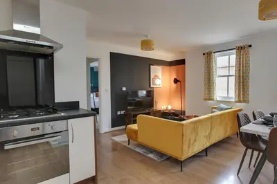 a kitchen and living room with a yellow couch at Two Bedroom Coach House - Free Allocated Parking for 2 vehicles - Central Colchester in Colchester