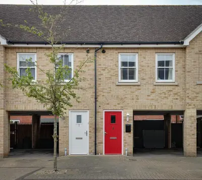 a brick building with a red door and a tree at Two Bedroom Coach House - Free Allocated Parking for 2 vehicles - Central Colchester in Colchester