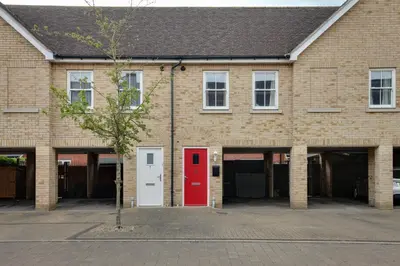 a brick building with a red door and a tree at Two Bedroom Coach House - Free Allocated Parking for 2 vehicles - Central Colchester in Colchester