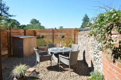 a patio with a table and chairs and a fence at May Barn, Ixworth in Ixworth