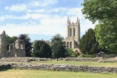 a church with a stone wall in front of a church at May Barn, Ixworth in Ixworth