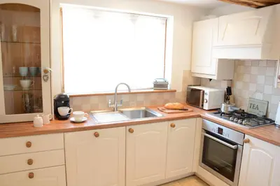 a kitchen with white cabinets and a sink and a window at May Barn, Ixworth in Ixworth