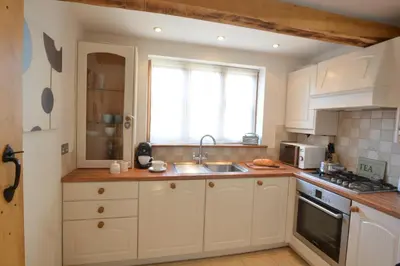 a kitchen with white cabinets and a sink and a window at May Barn, Ixworth in Ixworth