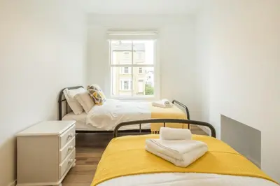 two beds in a small room with a window at Cosy Two Bedroom Apartment in Excellent Location in Chesterton